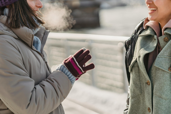 Two people having a discussion on a cold winter's day, with their breath heavily visible in the air.