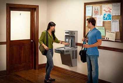 Two people using a hands free wall mounted water fountain 