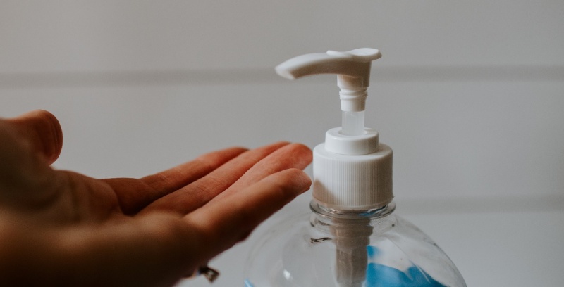 A hand placed under a handsanitiser.