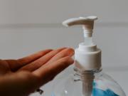 A hand placed under a handsanitiser. 